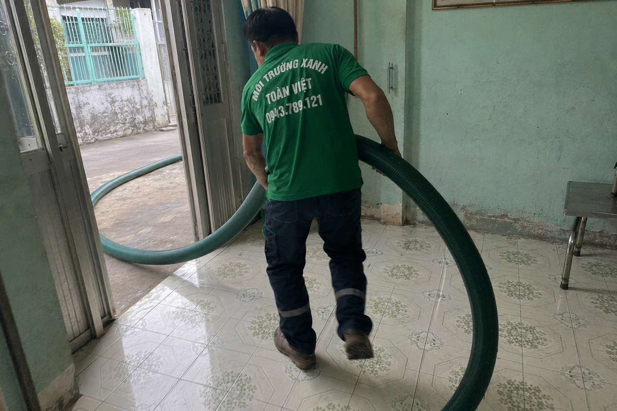 Nhân viên kéo ống hút qua bên trong nhà để tới vị trí hầm