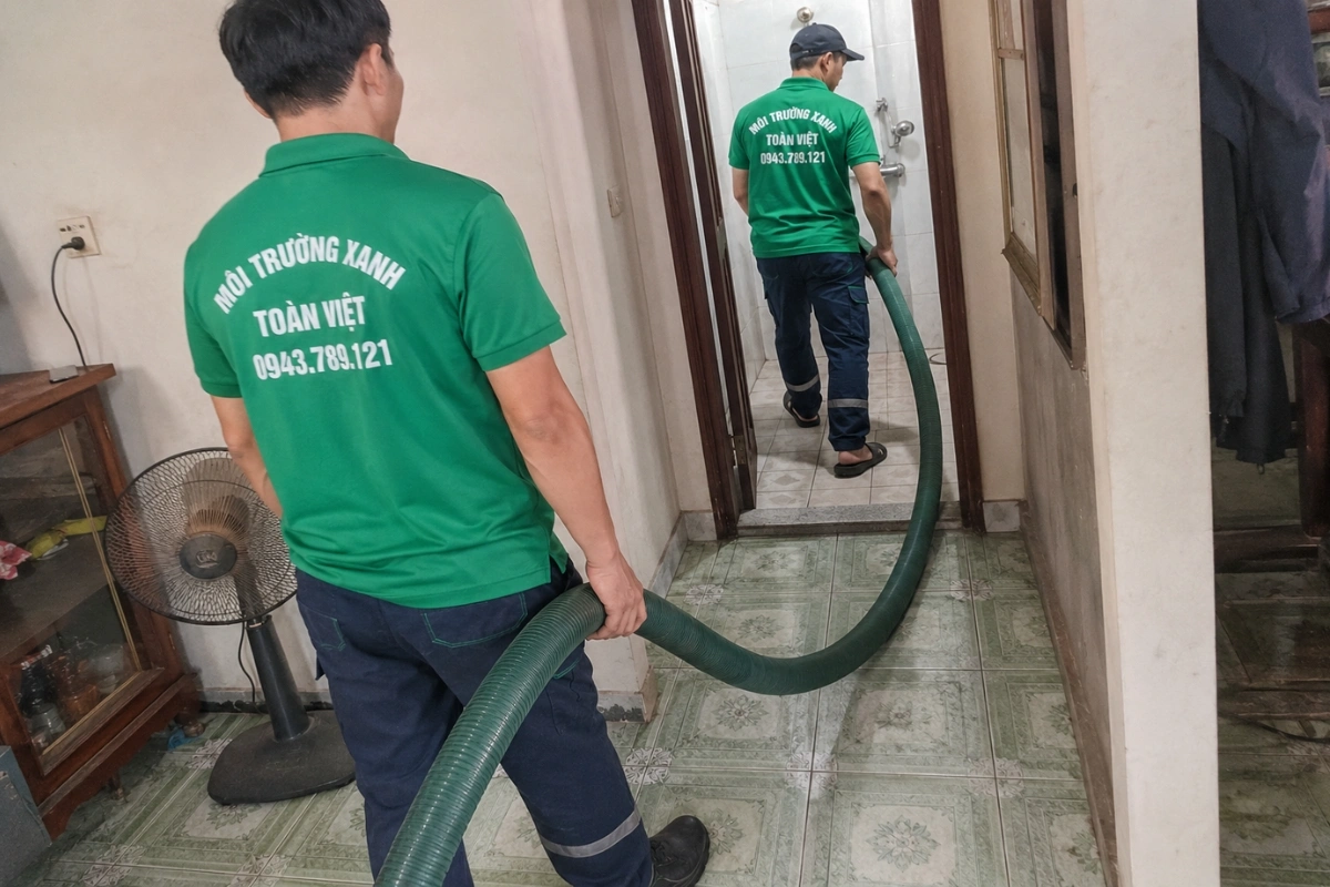 Thợ môi trường mang ống hút hầm cầu vào nhà dân