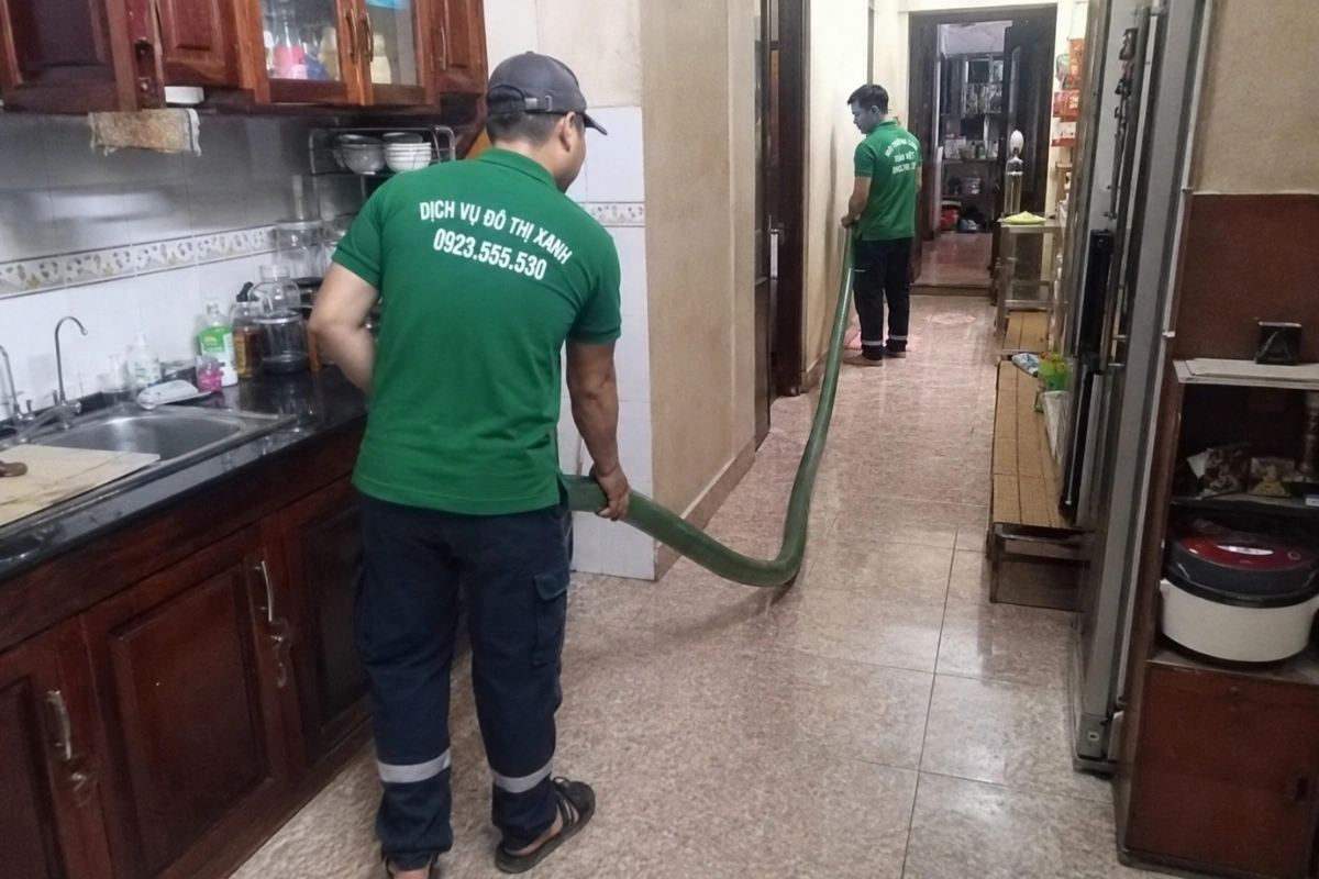 Nhân viên kéo ống hút hầm cầu vào nhà dân để thi công