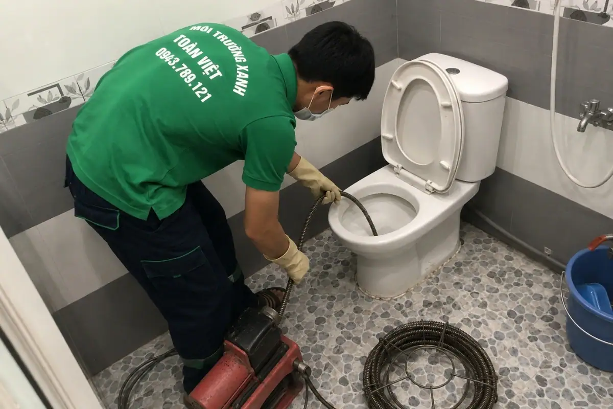 Kỹ thuật viên sử dụng thiết bị chuyên dụng xử lý bồn cầu bị tắc.