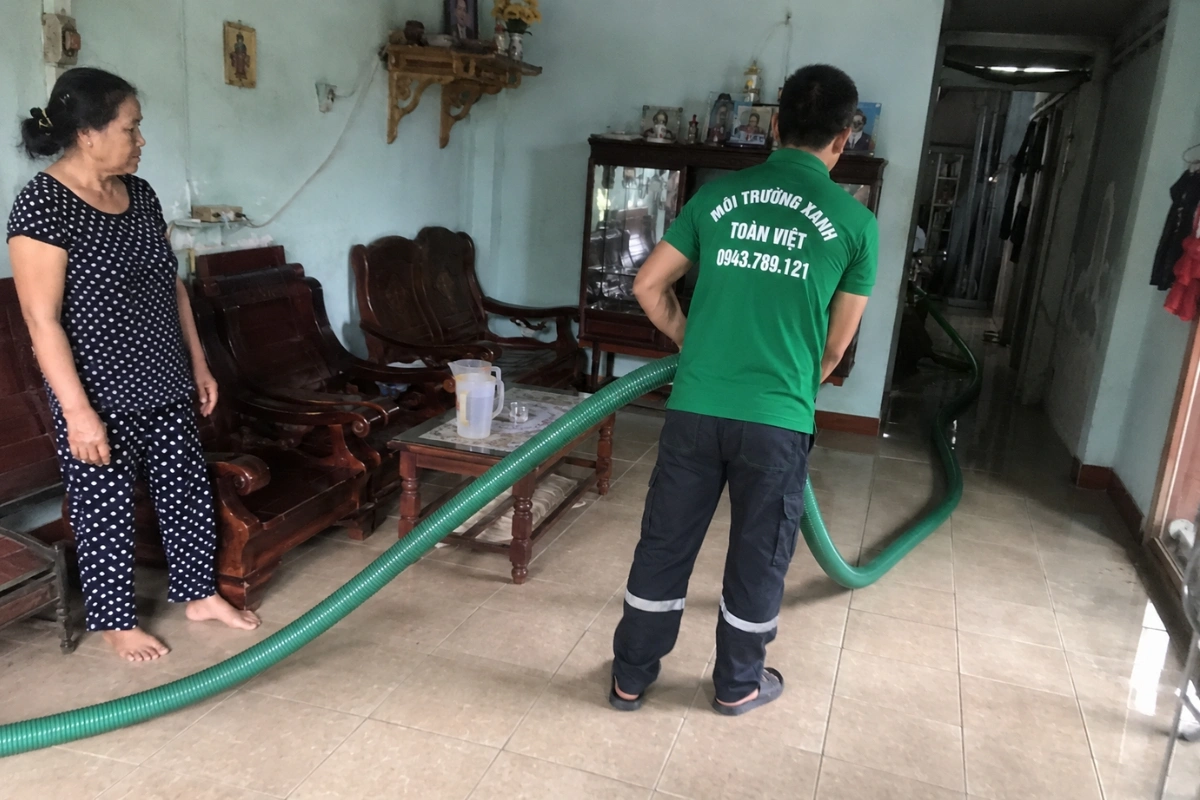 Nhân viên hút hầm cầu đưa ống vào khu vực phía sau nhà