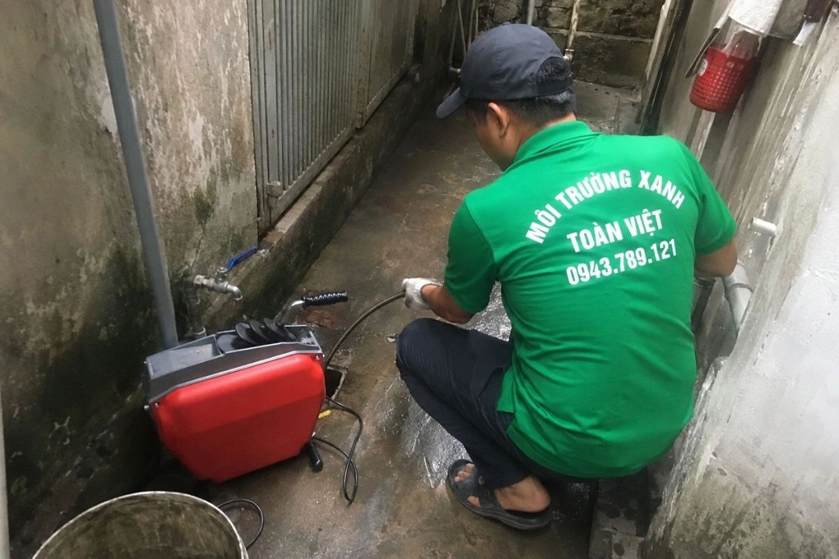 Nhân viên mặc đồng phục xanh đang khắc phục hiện tượng đường ống không thoát.