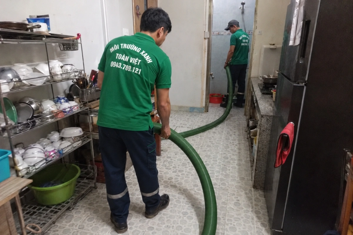 Nhân viên hút hầm cầu đưa ống vào khu vực phía sau nhà