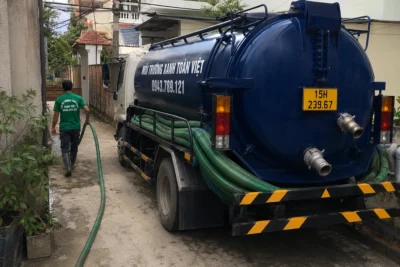 Hai nhân viên di chuyển cạnh xe hút hầm cầu chuyên dụng