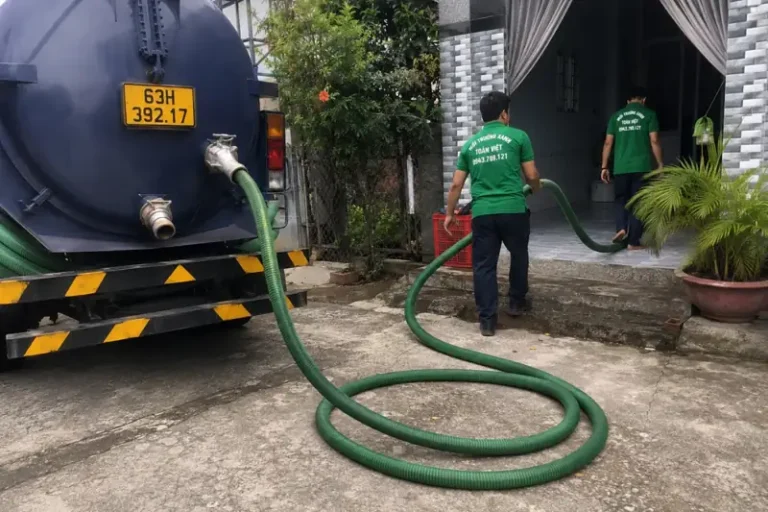Nhân viên dẫn ống từ xe bồn qua sân vào cửa nhà
