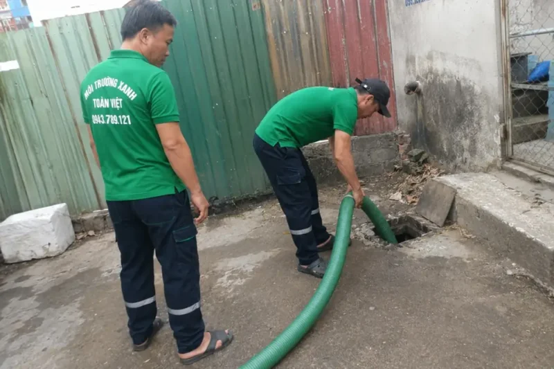 nhân viên thao tác ống hút cạnh nắp thăm