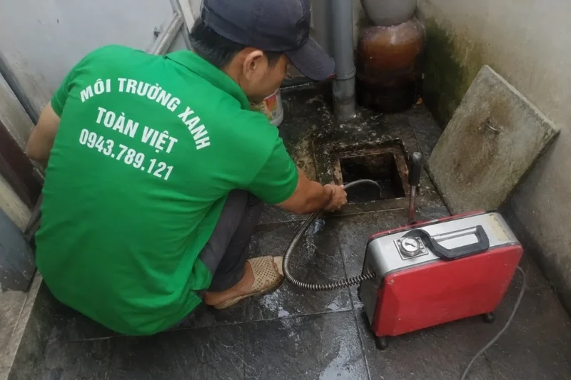 Nhân viên thao tác dây lò xo tại cửa thăm với máy màu đỏ
