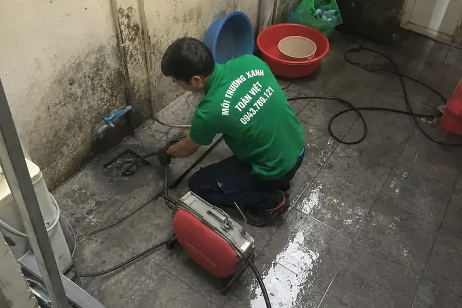Thợ thao tác tại phễu thu cạnh vòi nước