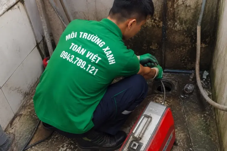 Nhân viên vận hành dây thông tại lỗ thoát gần tường