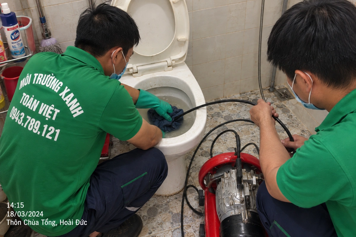 Hai kỹ thuật viên thao tác ống dẫn tại bồn cầu trong hồ sơ thôn Chùa Tổng, Hoài Đức.