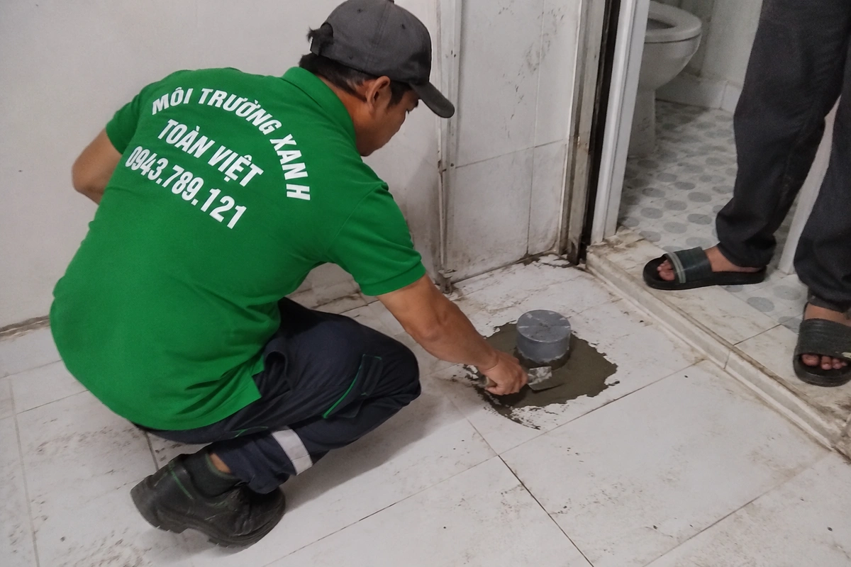 Nhân viên trét lại nắp hầm cầu sau khi hút xong