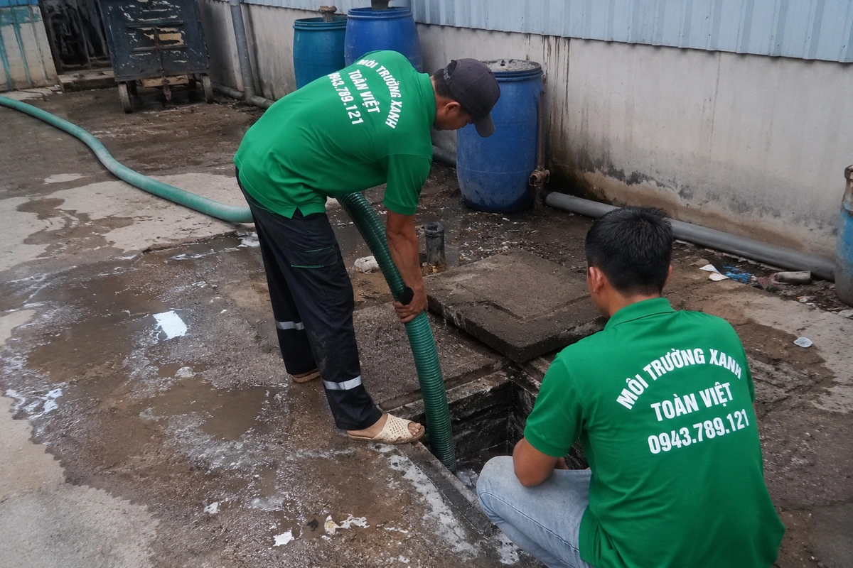 Hút Hầm Cầu Cẩm Xuyên 24/7, Phục Vụ Biển Thiên Cầm 11 Nhân viên đưa ống hút xuống hầm cầu bên hông nhà