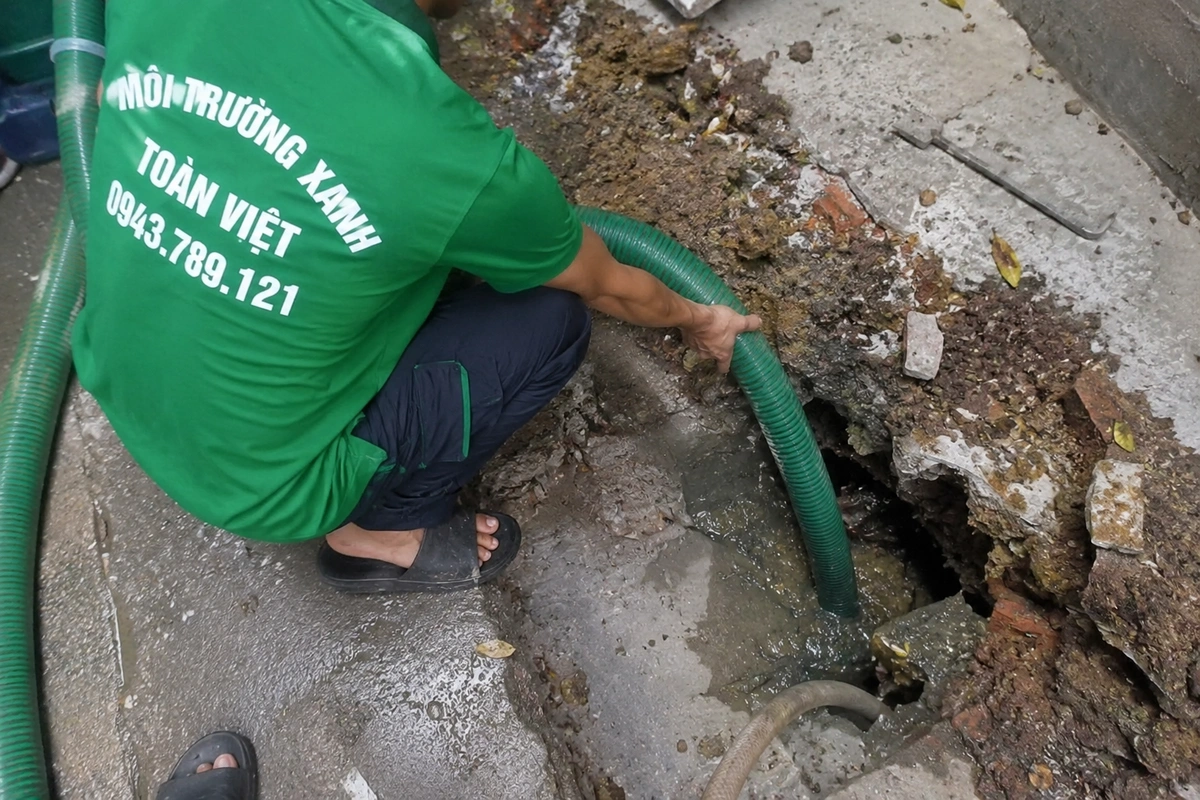Nhân viên đưa ống hút vào miệng hầm cầu ngoài sân