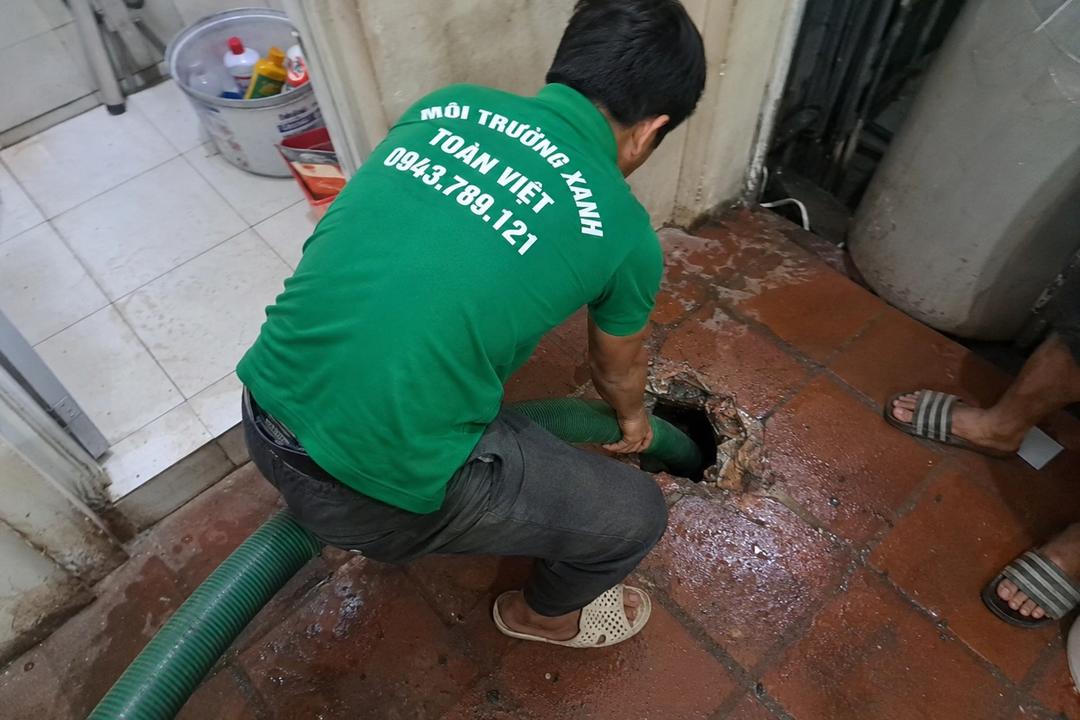 Nhân viên đưa ống hút xuống miệng hầm cầu