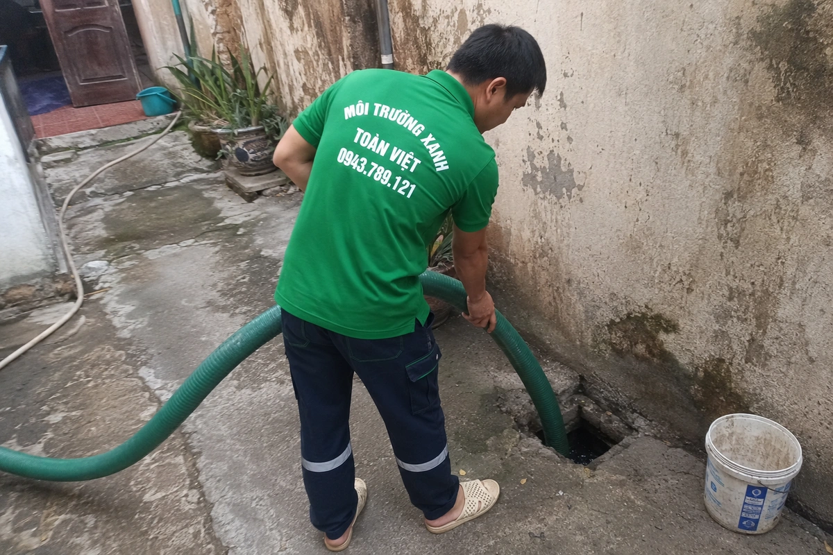 Nhân viên đưa ống hút xuống miệng hầm cầu