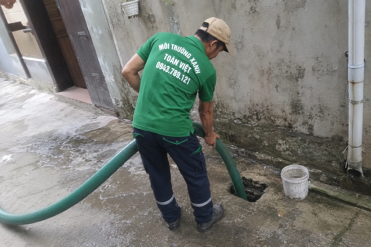 Nhân viên đưa ống hút xuống miệng hầm cầu