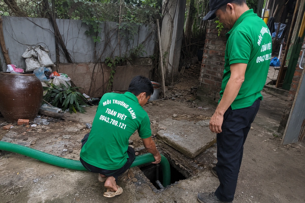 Nhân viên đưa ống hút xuống miệng hầm cầu