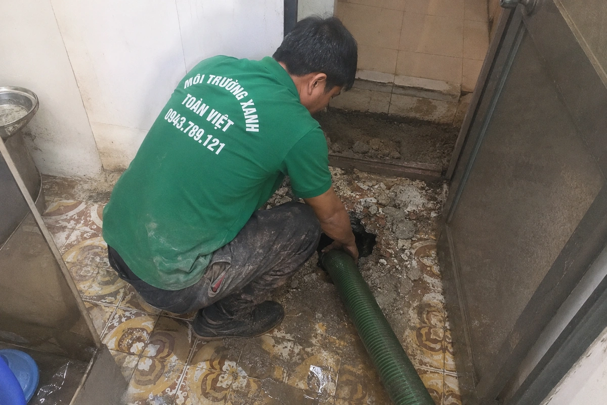 Nhân viên hút hầm cầu tại vị trí nắp hầm trong nhà tắm