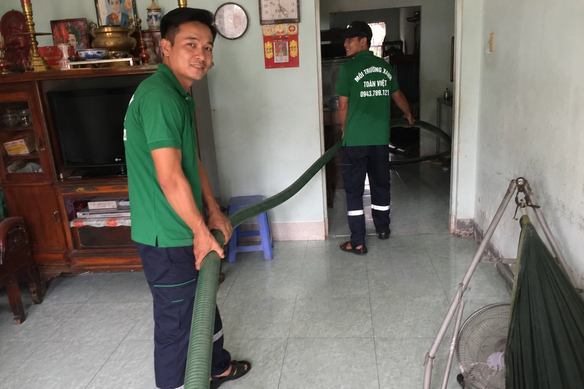 Nhân viên kéo ống hút vào trong nhà để tới miệng hầm