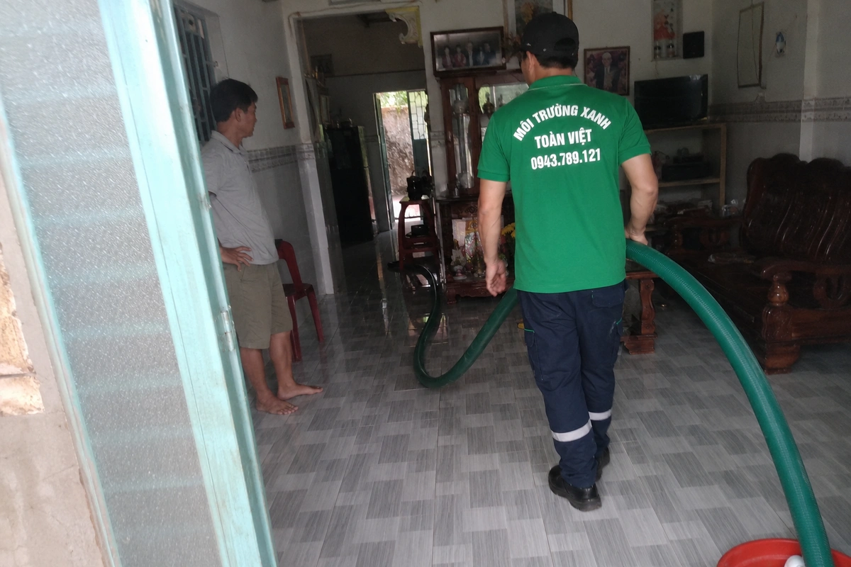 Hút Hầm Cầu Thăng Bình 24/7, Báo Giá Theo m³ 11 Nhân viên kéo ống hút vào trong nhà để tới miệng hầm
