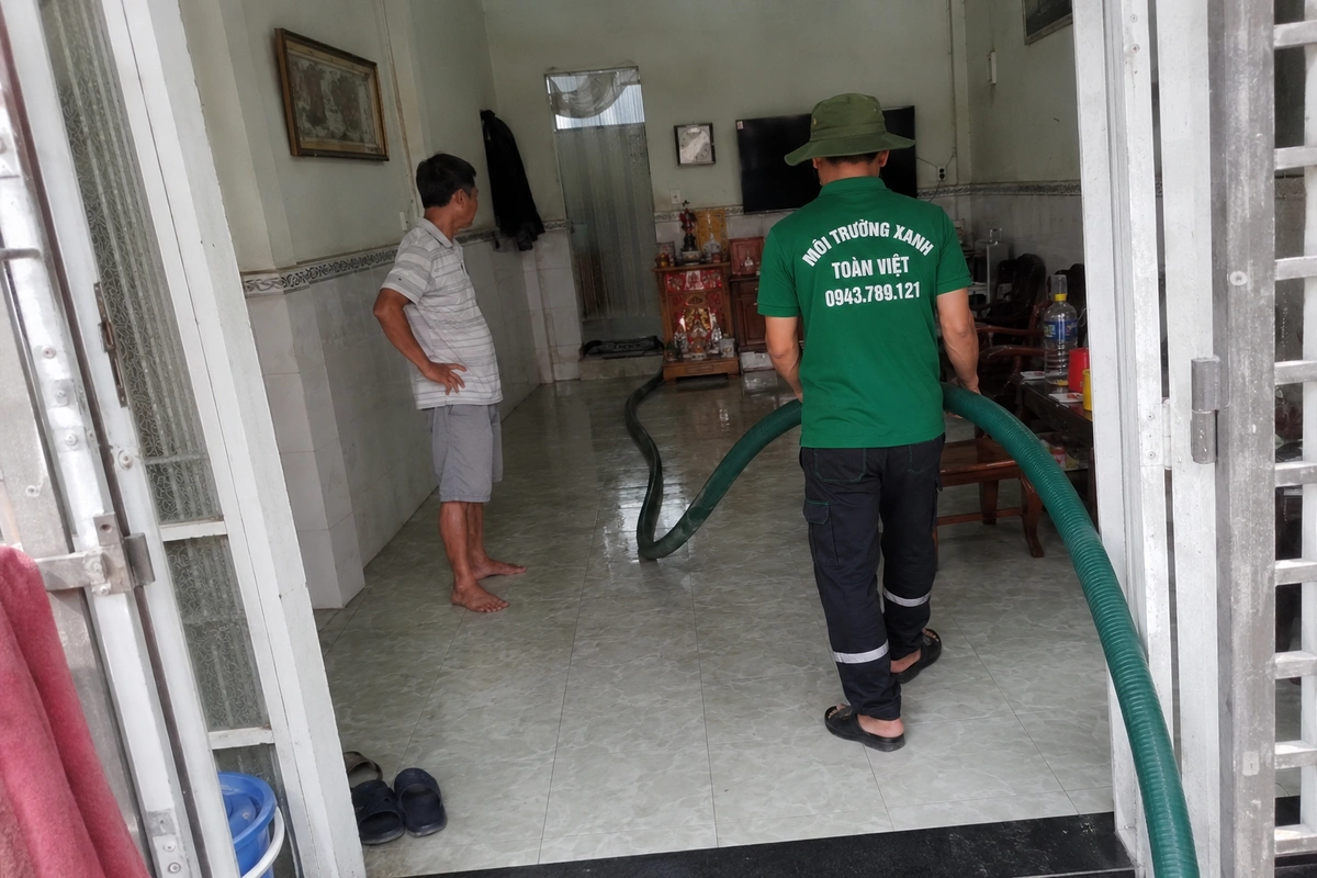 Nhân viên kéo ống hút vào trong nhà để tới miệng hầm