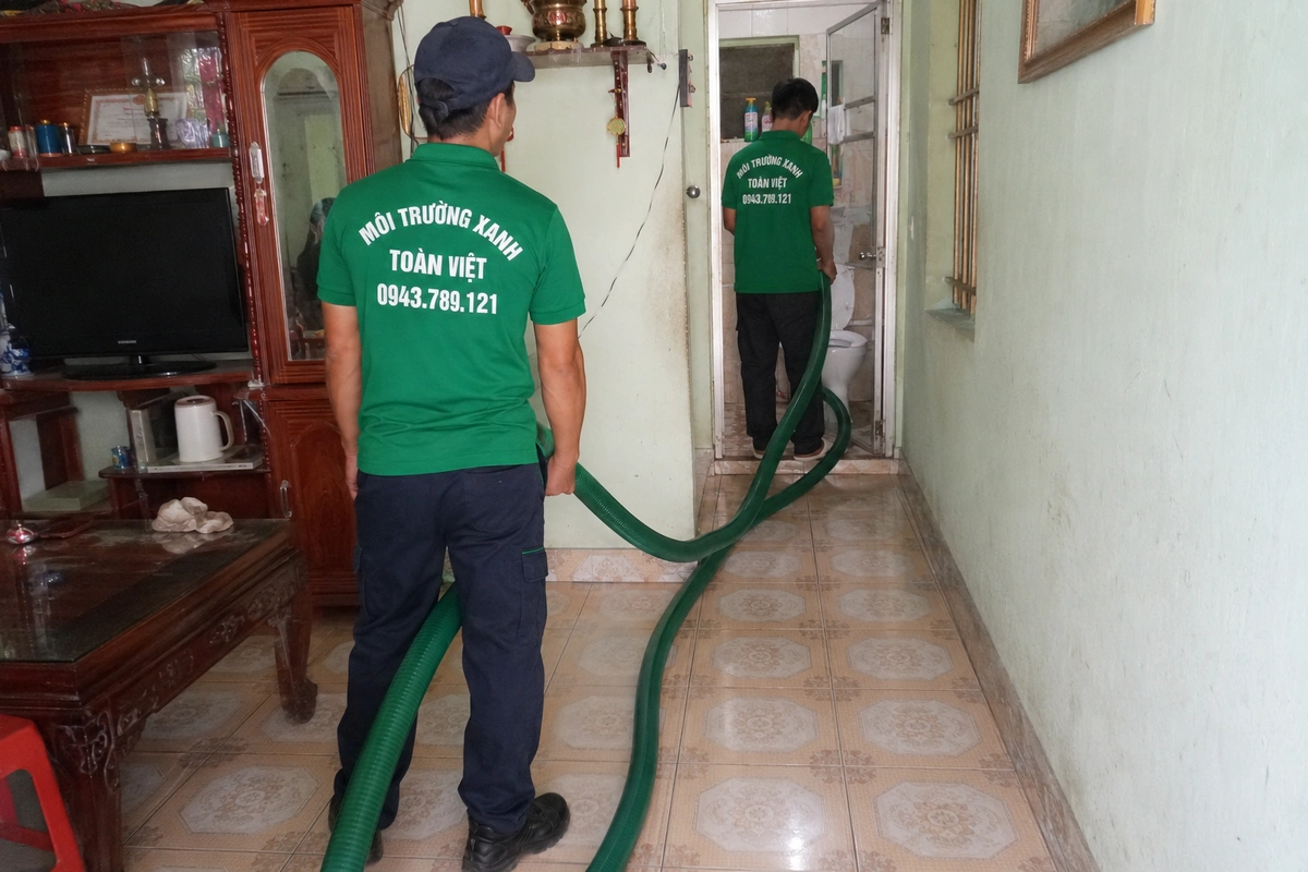 Hút Hầm Cầu TP Vinh 24/7, Tính m³ Minh Bạch | Gọi Ngay 13 Nhân viên kéo ống hút vào trong nhà để tới miệng hầm