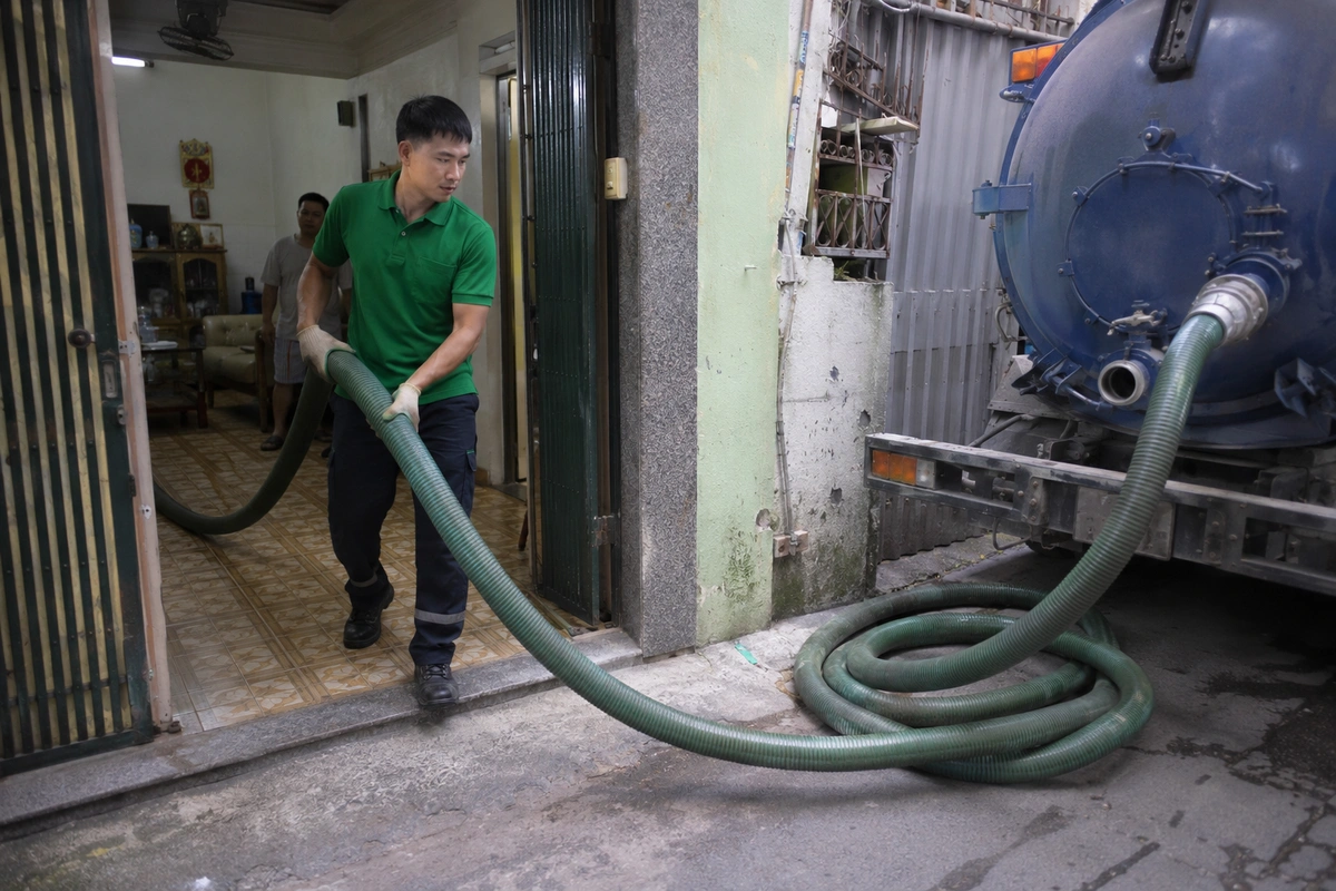 Nhân viên kéo ống hút vào trong nhà để tới miệng hầm