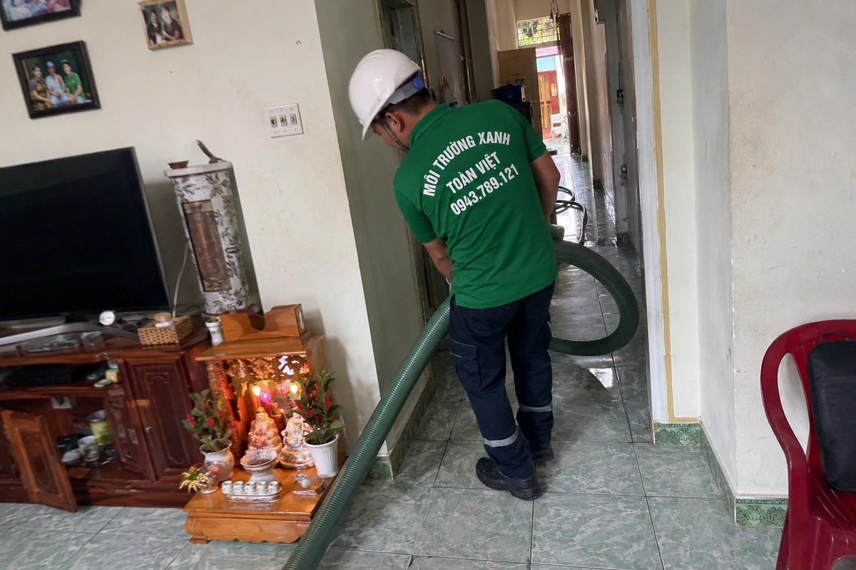 Nhân viên kéo ống hút vào trong nhà để tới miệng hầm