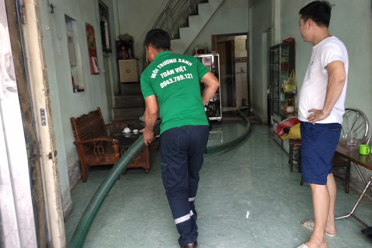 Nhân viên kéo ống hút vào trong nhà để tới miệng hầm