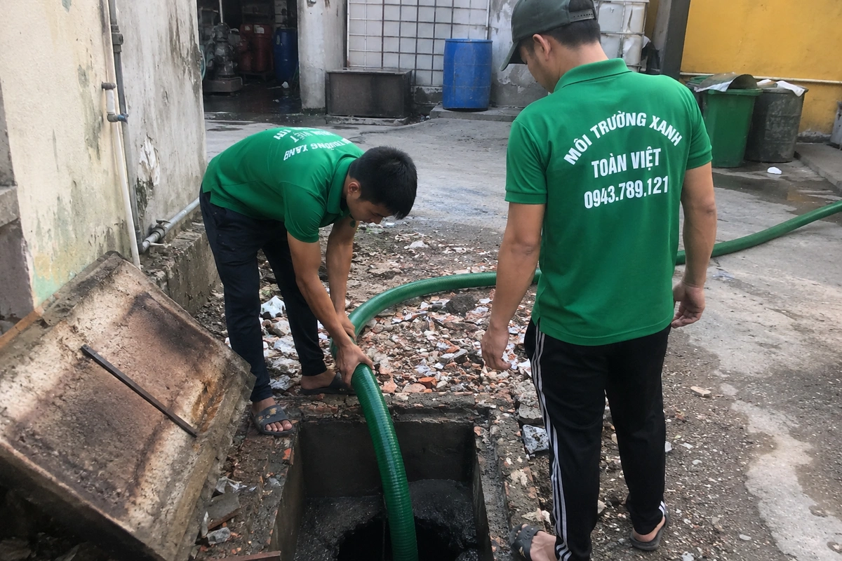 Nhân viên mở nắp hầm cầu ngoài sân trước khi thi công