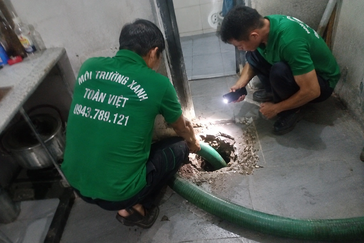Hai nhân viên soi đèn kiểm tra bên trong miệng hầm cầu