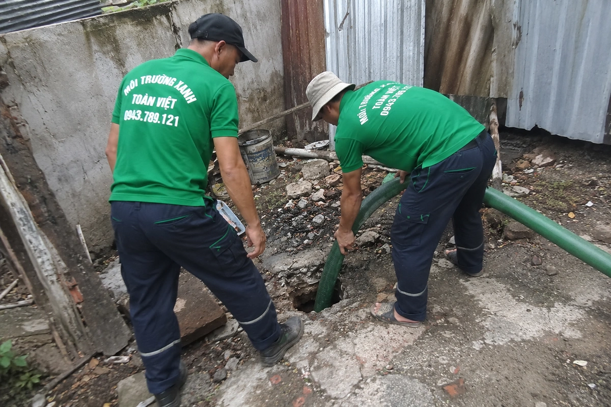 Nhân viên kiểm tra miệng hầm cầu trong lúc hút