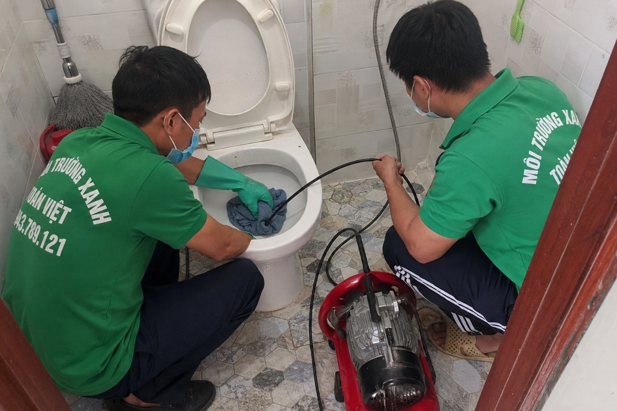 Kỹ thuật viên đưa dây lò xo vào bồn cầu để phá điểm tắc