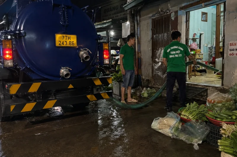 Xe bồn và hai nhân viên Toàn Việt đưa ống vào khu nhà
