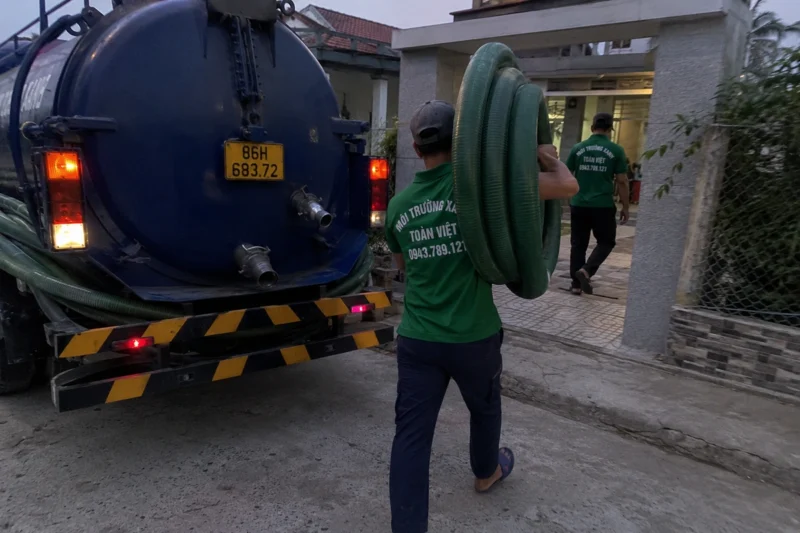 Nhân viên thu xếp cuộn ống bên xe bồn – hút hầm cầu Bình Thuận, Môi Trường Xanh Toàn Việt