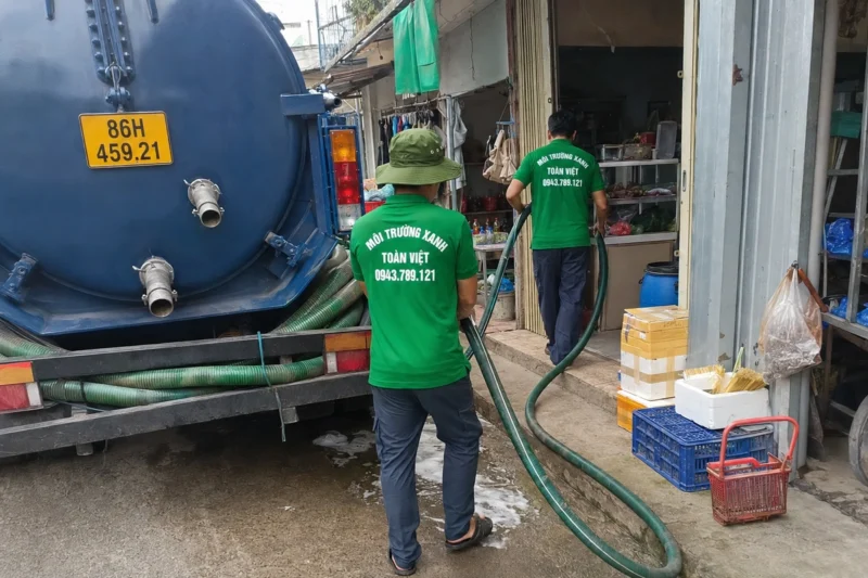 Nhân viên dẫn ống hút từ phía sau xe vào lối nhà – hút hầm cầu Bình Thuận, Môi Trường Xanh Toàn Việt