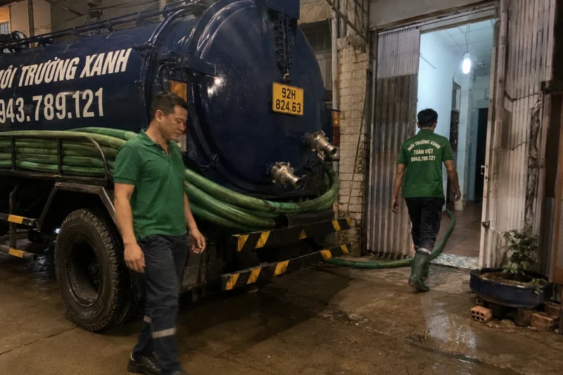 Hút hầm cầu Quảng Nam giá rẻ uy tín | Toàn Việt 47 Nhân viên và đường ống hút trong lối vào nhà