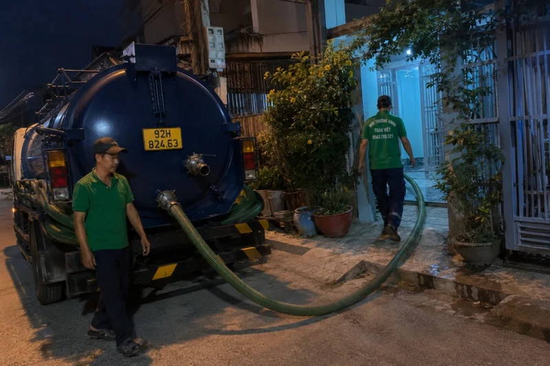 Hút hầm cầu Quảng Nam giá rẻ uy tín | Toàn Việt 41 Tuyến ống hút và nhân viên phía sau xe buổi tối