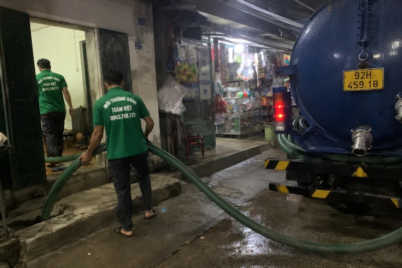 Hút hầm cầu Quảng Nam giá rẻ uy tín | Toàn Việt 32 Nhân viên dẫn ống từ xe vào lối nhà buổi tối