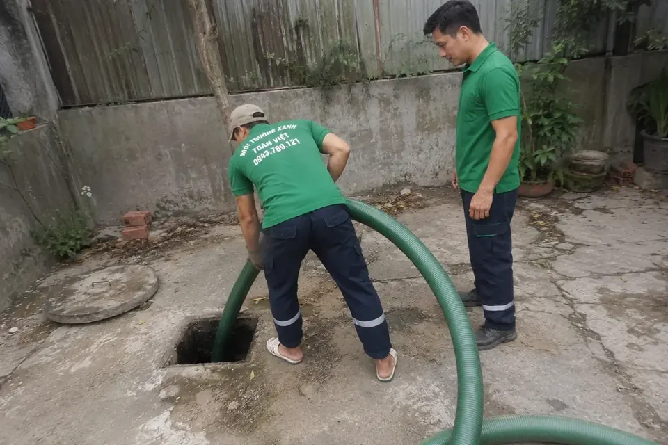 Hai nhân viên bên miệng hầm đã mở nắp