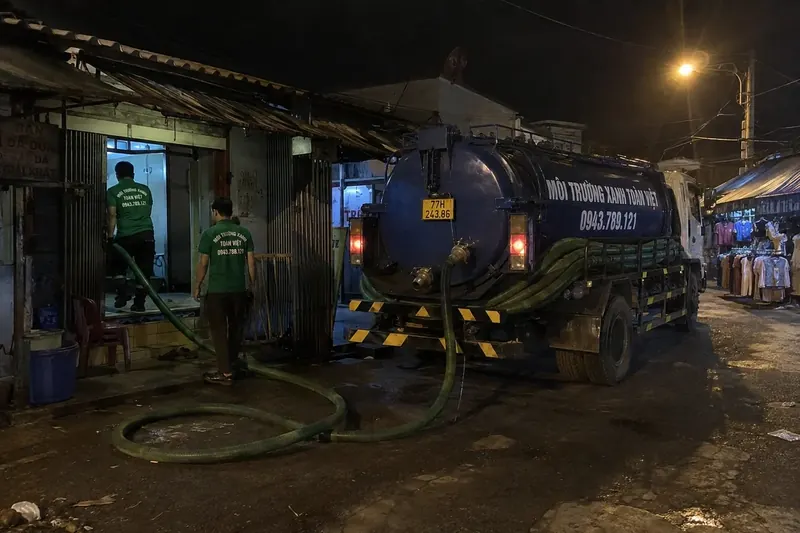 Hút hầm cầu Bình Định – Môi Trường Xanh Toàn Việt 39 Xe bồn, nhân viên và ống hút ở sân lúc tối