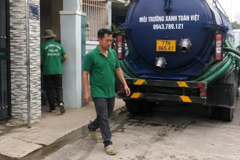 Hút hầm cầu Bình Định – Môi Trường Xanh Toàn Việt 43 Nhân viên Toàn Việt đứng bên đầu nối ống ở xe