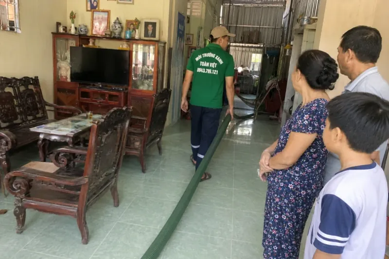 Hút hầm cầu Bình Thủy uy tín, giá rẻ | Toàn Việt 13 Nhân viên Toàn Việt dẫn ống hút qua khu sinh hoạt