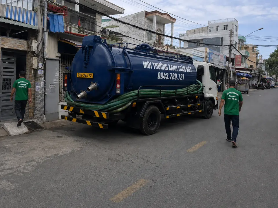 Xe bồn đỗ cạnh nhà, nhân viên đứng quan sát phía trước.