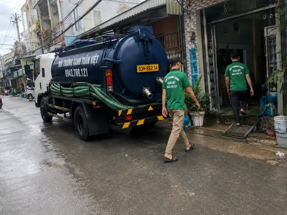 Hai nhân viên gần cửa nhà bên xe bồn chuyên dụng.