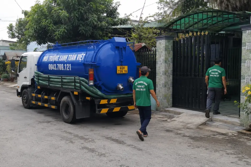 Nhân viên di chuyển cạnh xe bồn trước nhà