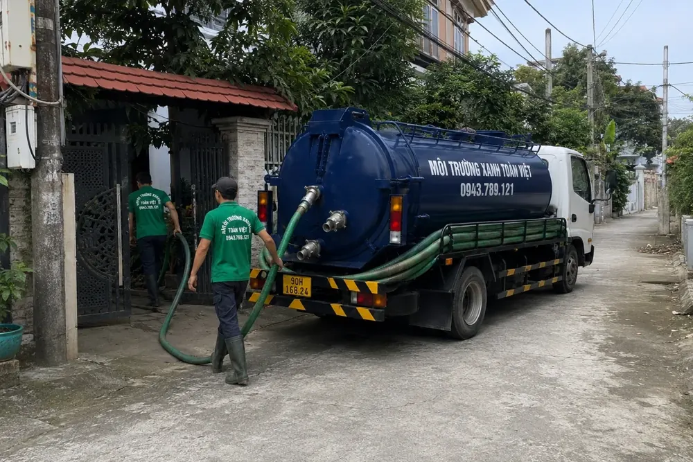 Nhân viên đứng cạnh xe bồn và đầu nối ống.