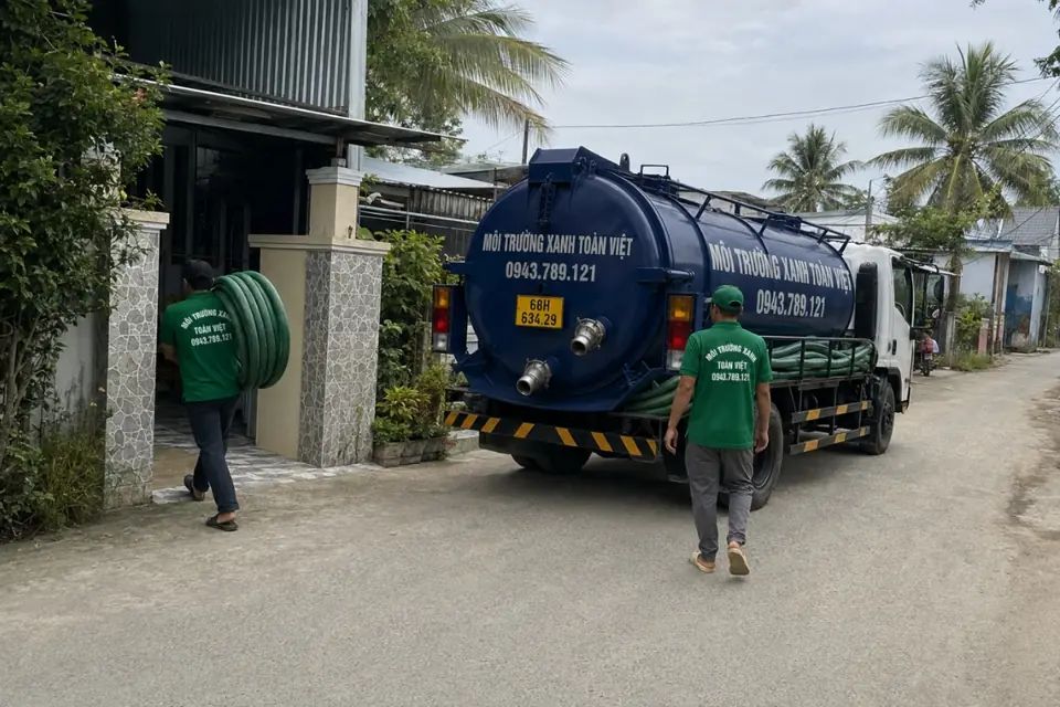 Hai nhân viên dẫn ống bên xe bồn đỗ trên đường