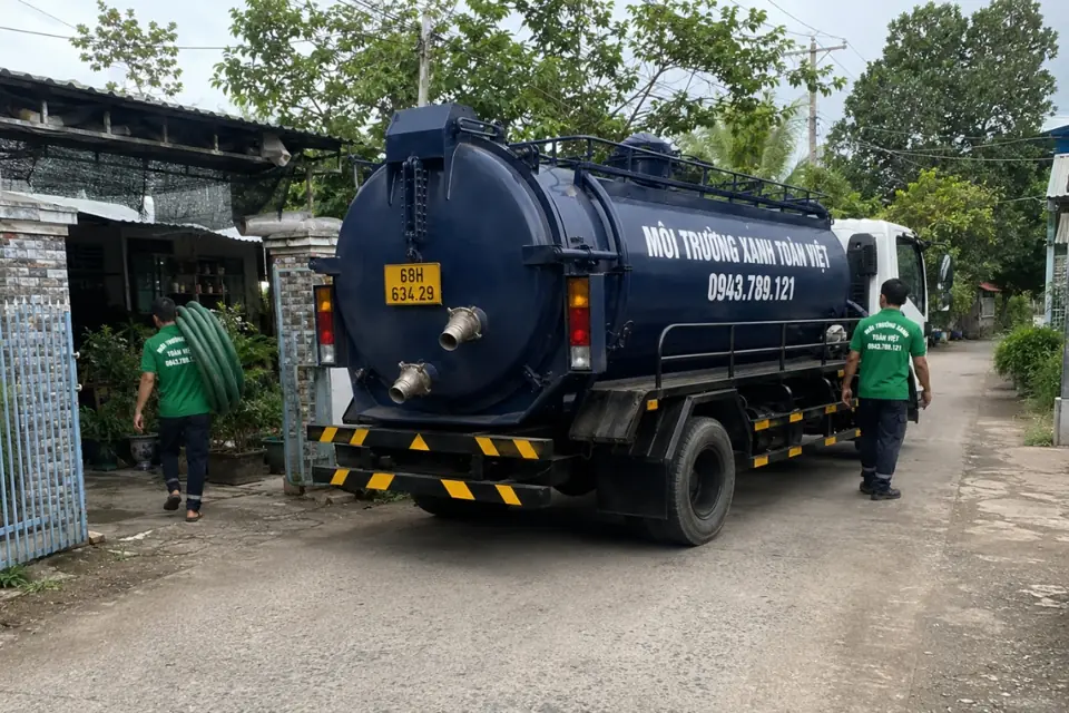 Xe bồn dừng bên cổng nhà, nhân viên đứng cạnh ống