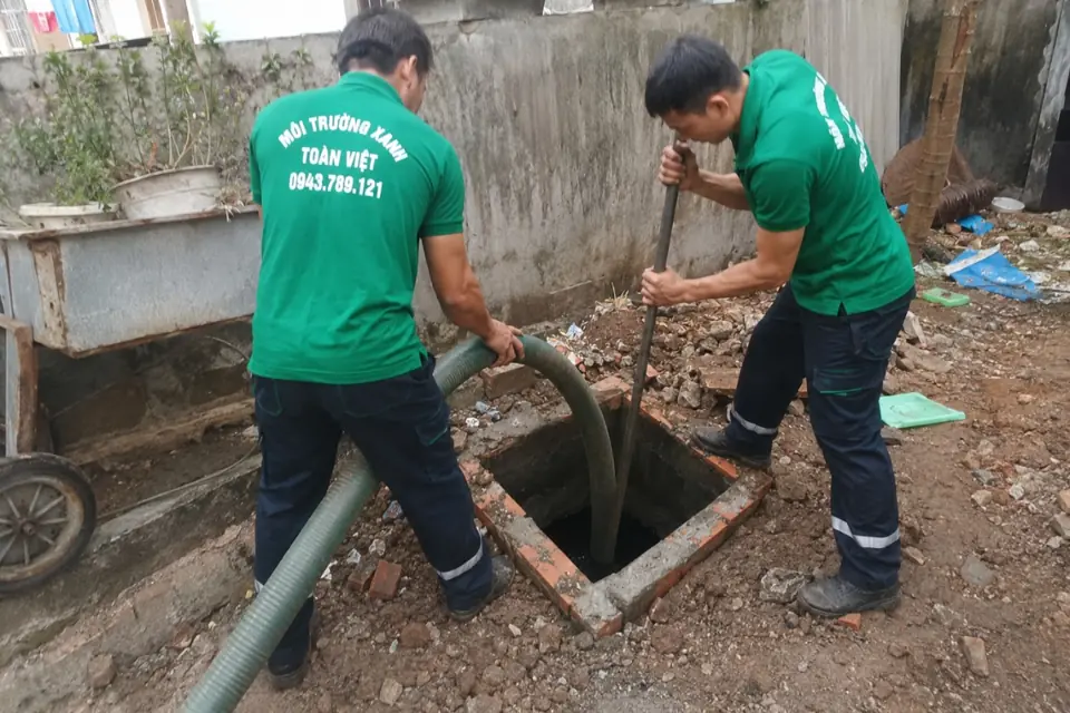 Hai nhân viên phối hợp thao tác tại hầm ngoài sân